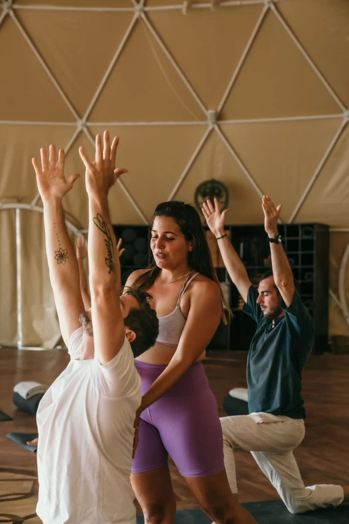 A yoga instructor gently correcting a student's posture during a class at Alaya Panama